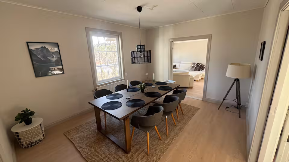 Matsal med långt bord för åtta personer under en svart taklampa